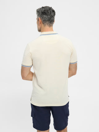 Cremefarvet RedGreen herrepolo med marine- og lyseblå kontraststriber ved krave og ærmer og diskret sejlsportslogo på brystet